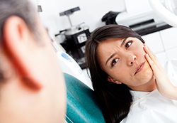 woman at dentist holding jaw in pain, has toothache needs root canal, Monmouth Junction, NJ